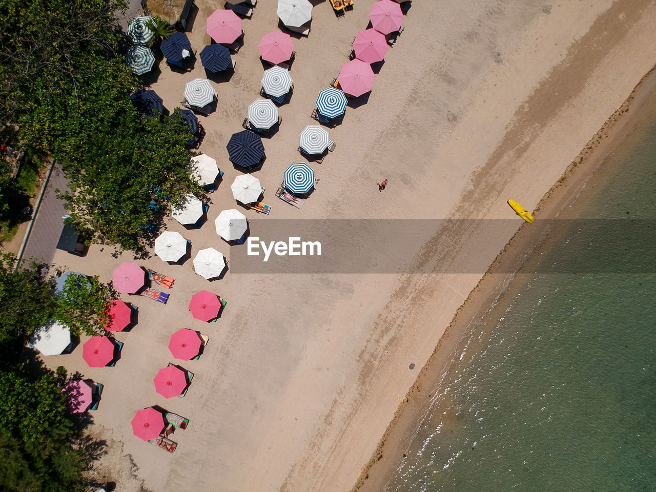 HIGH ANGLE VIEW OF MULTI COLORED UMBRELLAS ON SAND