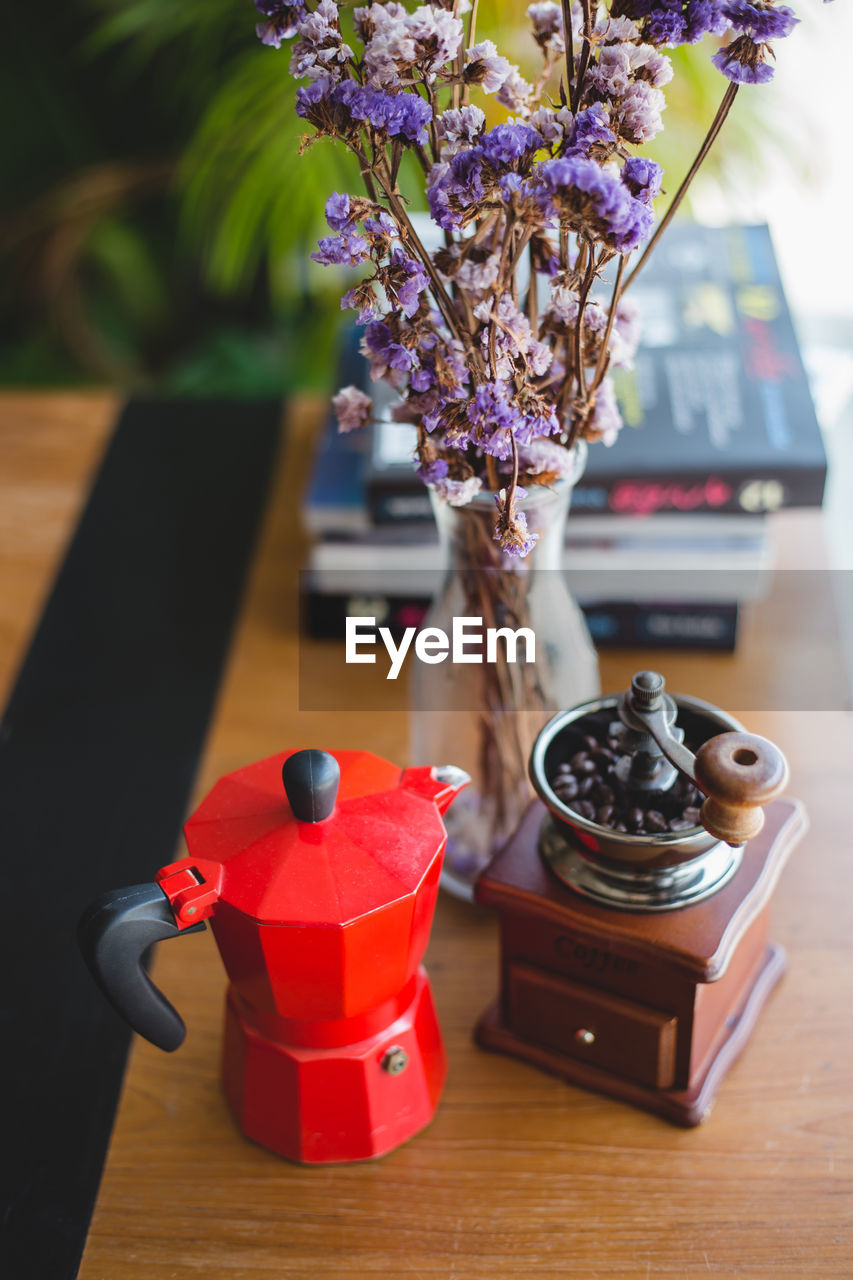 Coffee grinder by flower vase on table