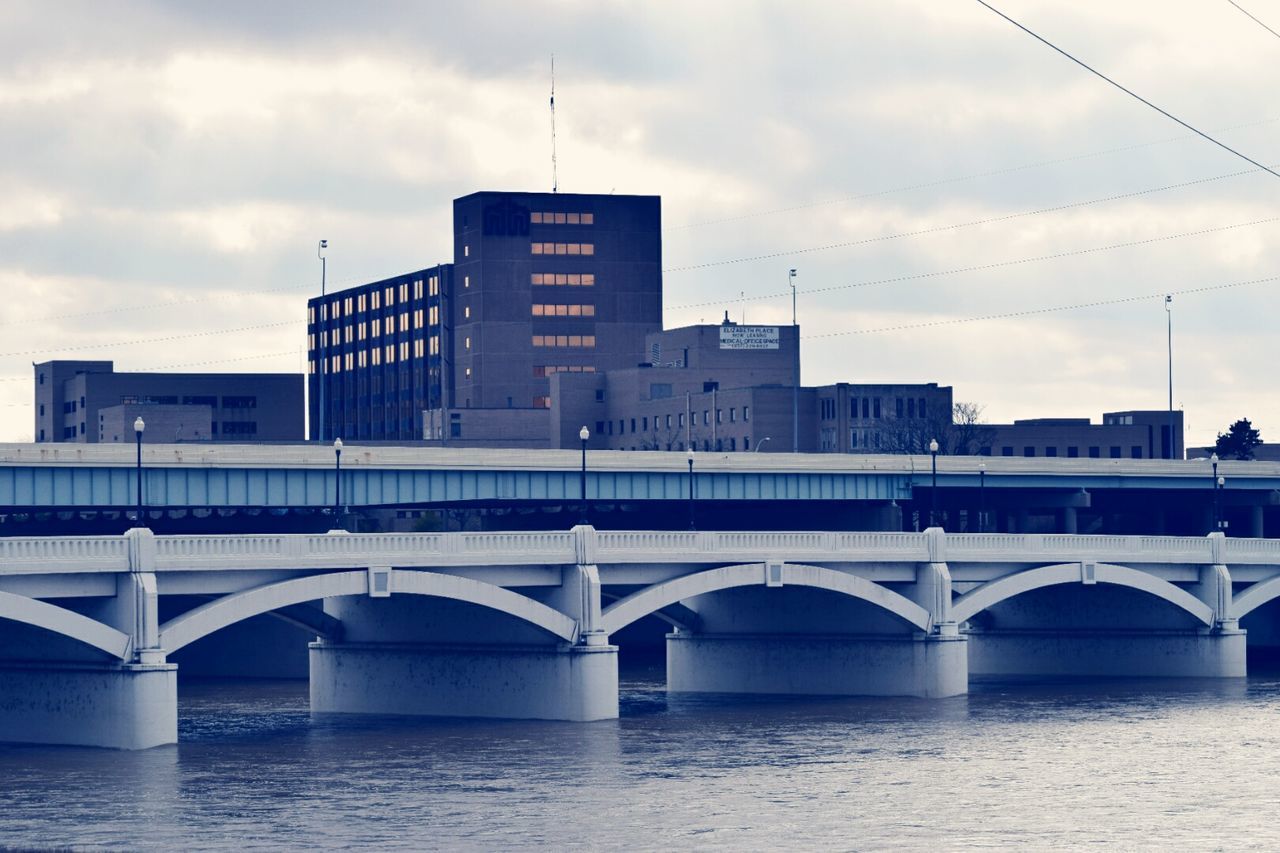 Bridge over river against cloudy sky