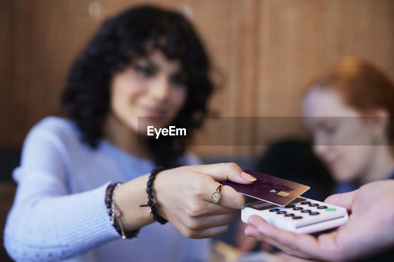 Young woman paying with card in cafe