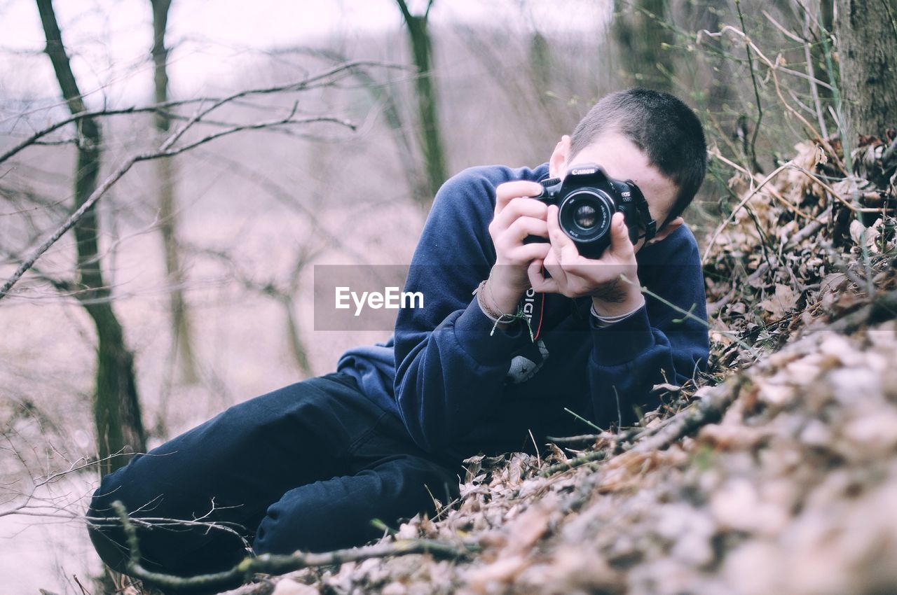 YOUNG MAN PHOTOGRAPHING IN GRASS