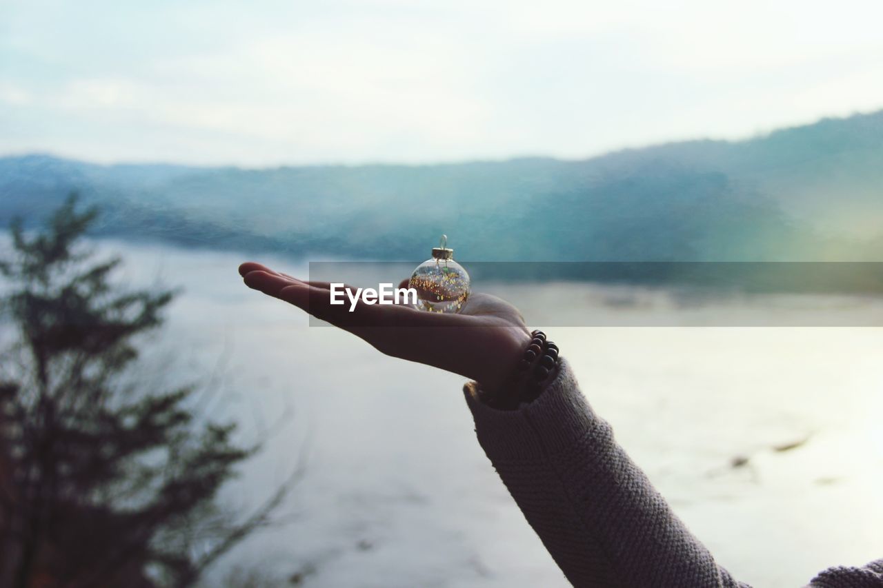 Close-up of hand holding bauble against lake