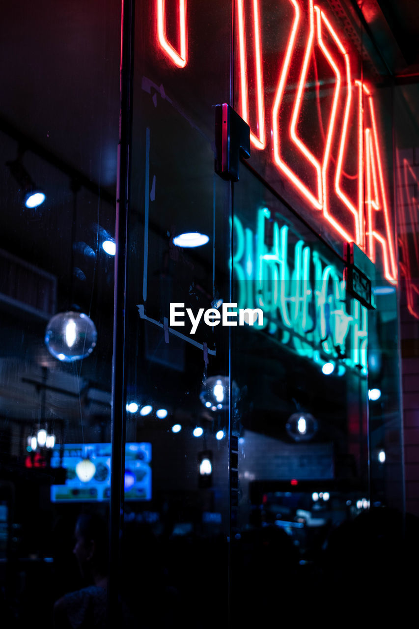 VIEW OF ILLUMINATED SIGN ON BUILDING AT NIGHT