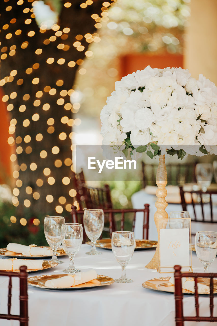 Beautiful outdoor receprion venue - white tablecloths, golden plates, white roses centerpieces