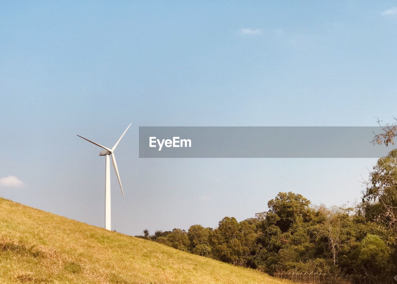 WIND TURBINES ON FIELD AGAINST SKY