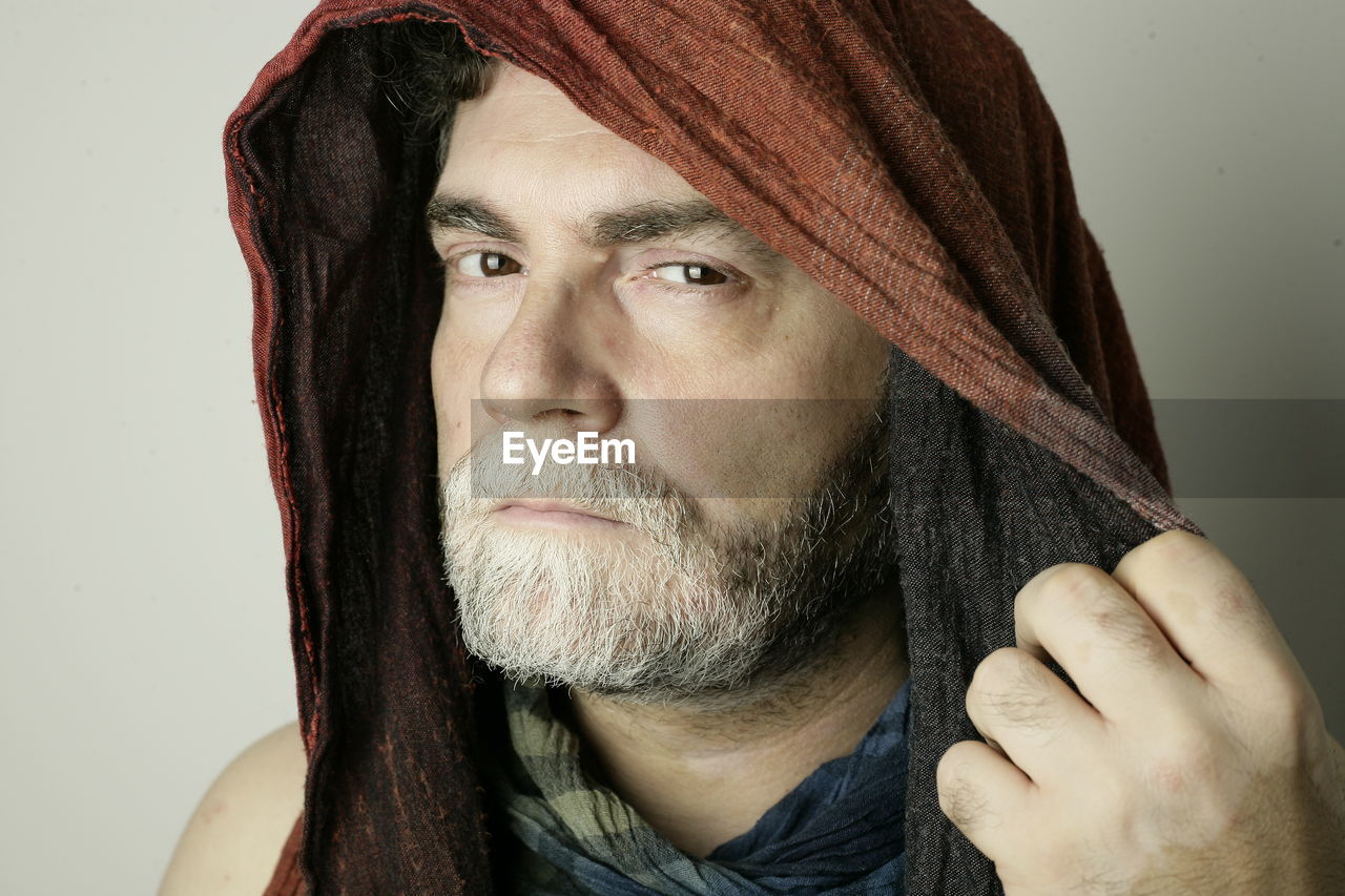 Portrait of man wearing scarf against white background