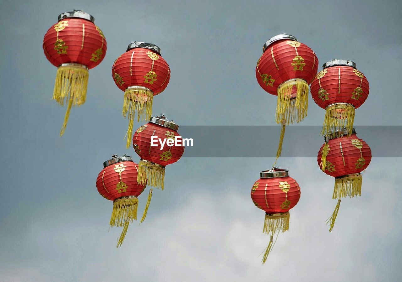 Low angle view of lanterns hanging against cloudy sky