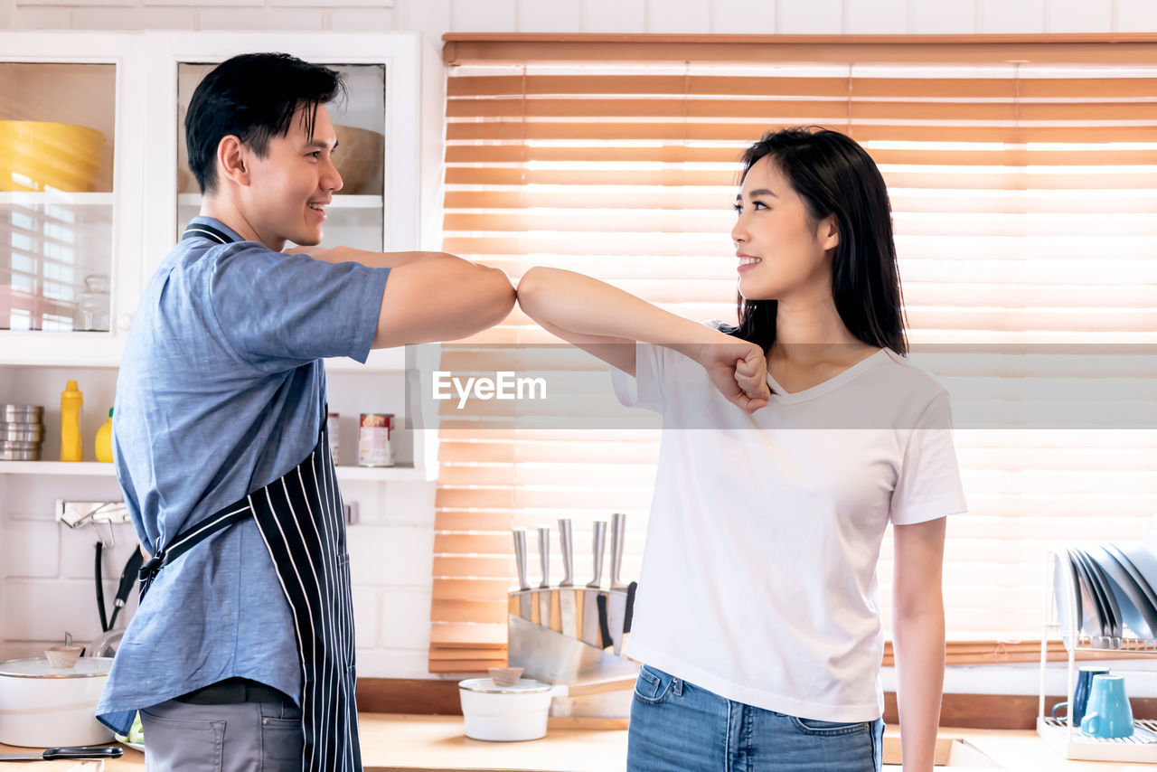 SIDE VIEW OF A YOUNG COUPLE STANDING AGAINST THE WALL