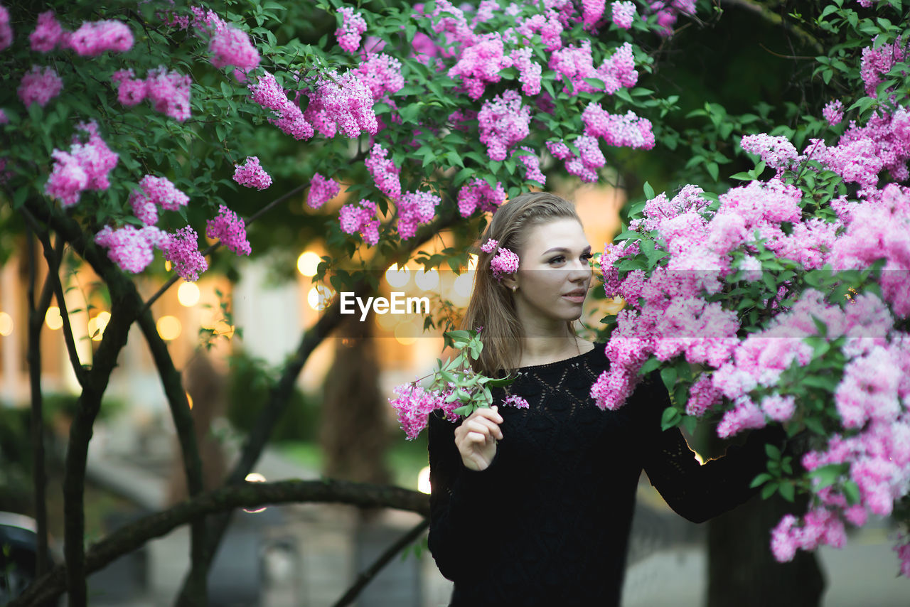 Young woman by purple flowers on branches