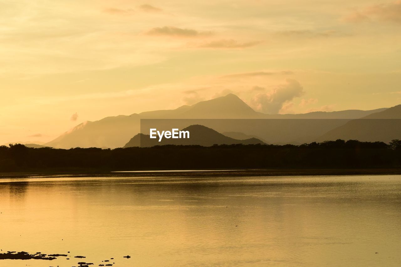 SCENIC VIEW OF LAKE AND MOUNTAINS AGAINST SKY DURING SUNSET