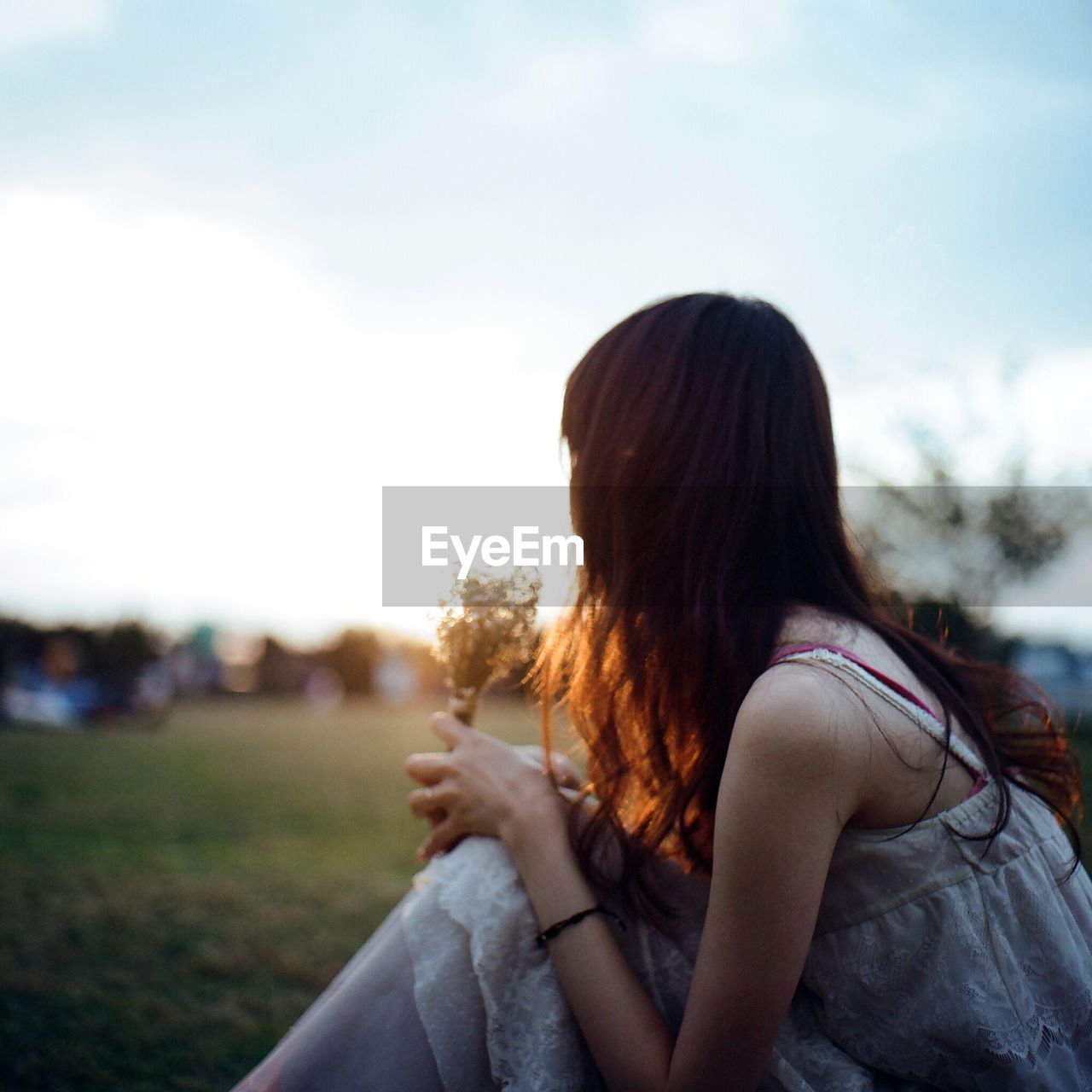 Woman sitting on field against sky