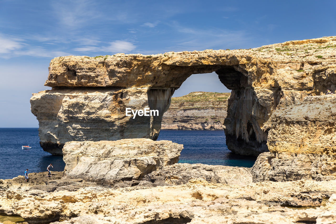 Rock formation by sea against sky