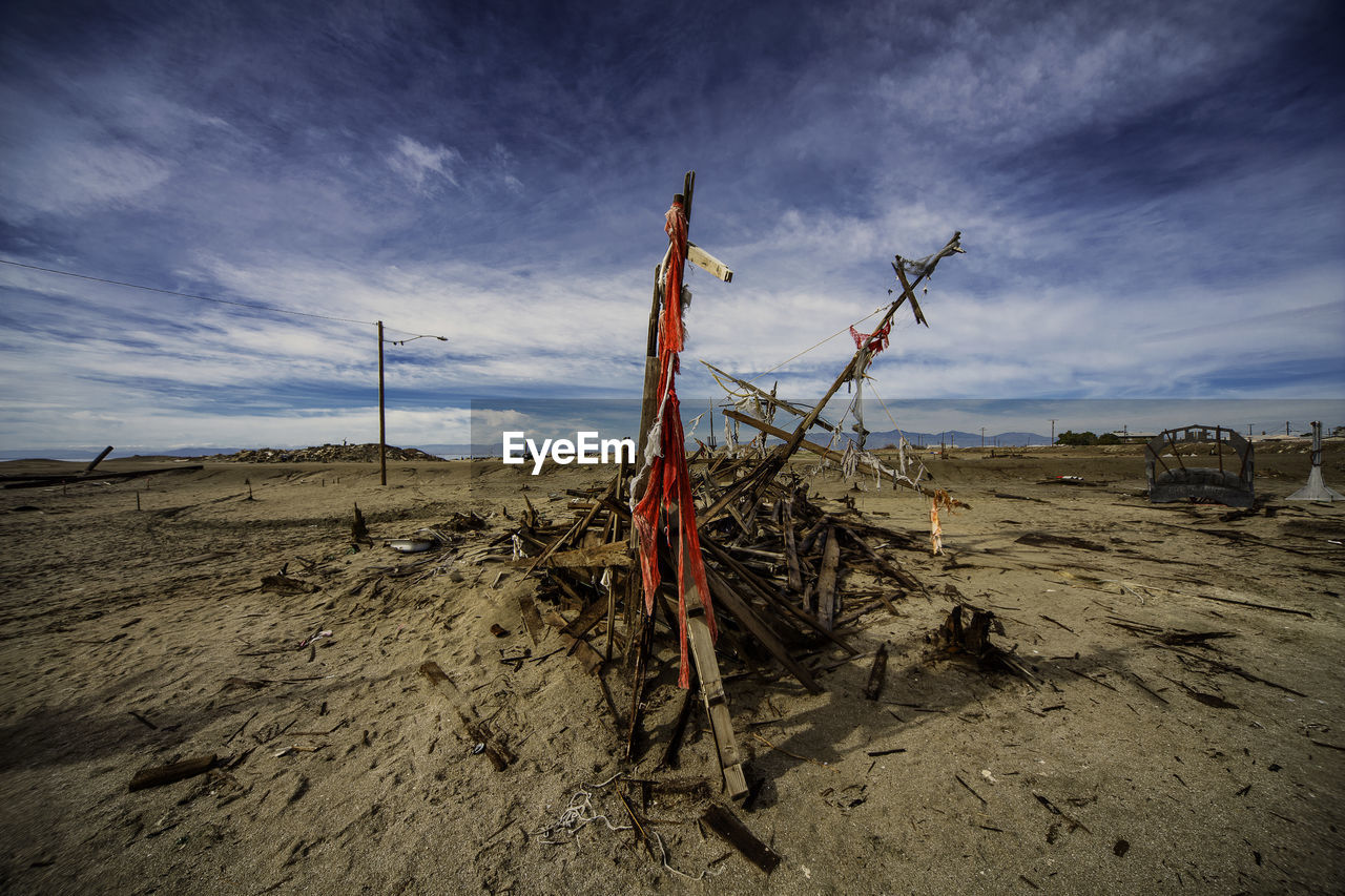 Driftwood on sand at beach against sky