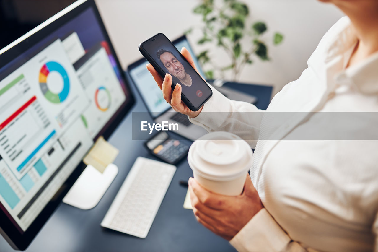 Businesswoman having video chat on mobile phone. businesswoman working with data on charts in office