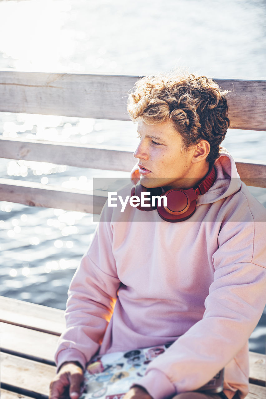 Young man sitting on bench during sunny day