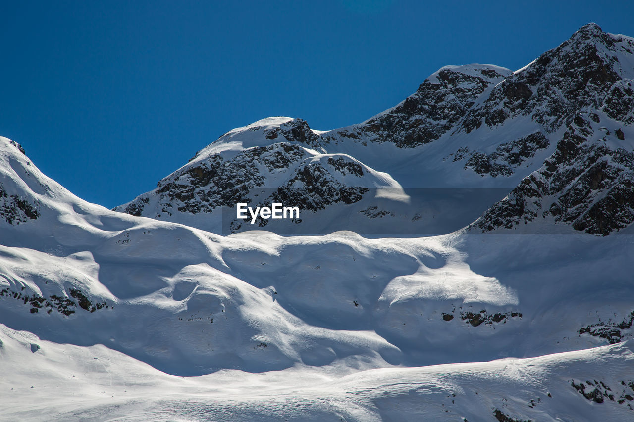 Scenic view of snowcapped mountains against clear blue sky