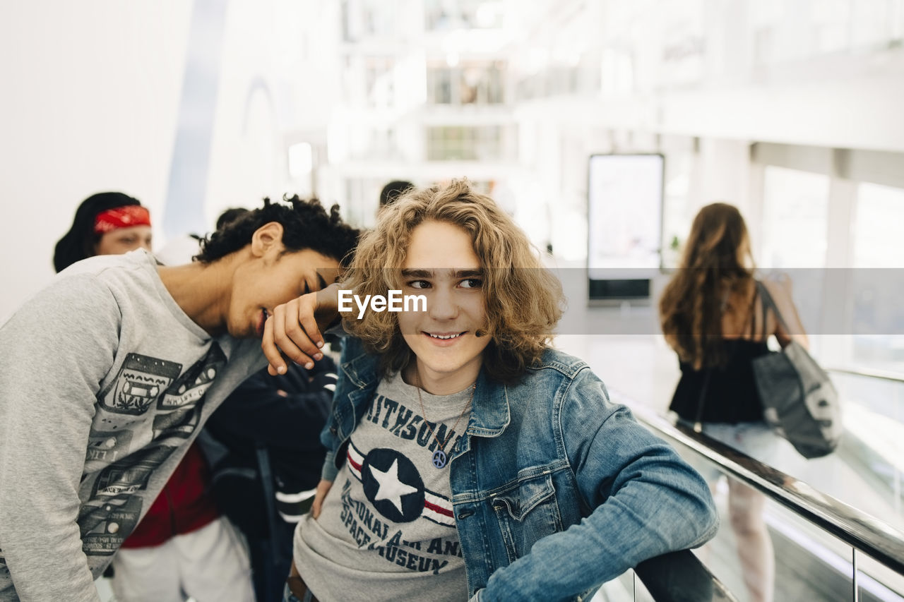 Friends standing on moving walkway in shopping mall