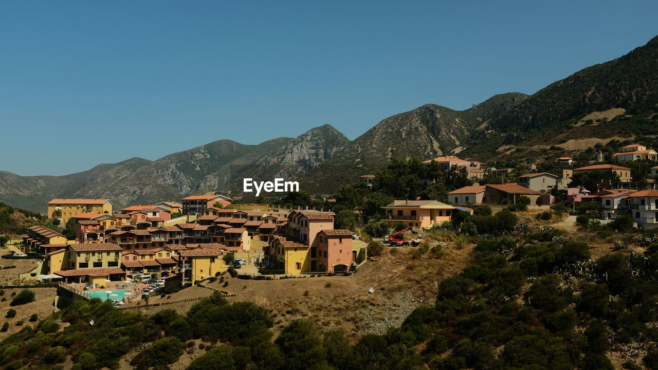 Town by mountains against clear blue sky