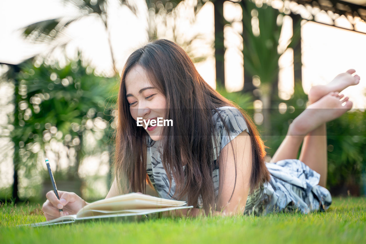 Smiling woman reading book in park