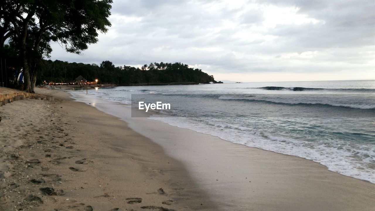 Scenic view of beach against cloudy sky