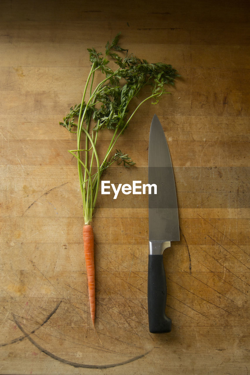 High angle view of carrot and knife on wooden table in kitchen at home