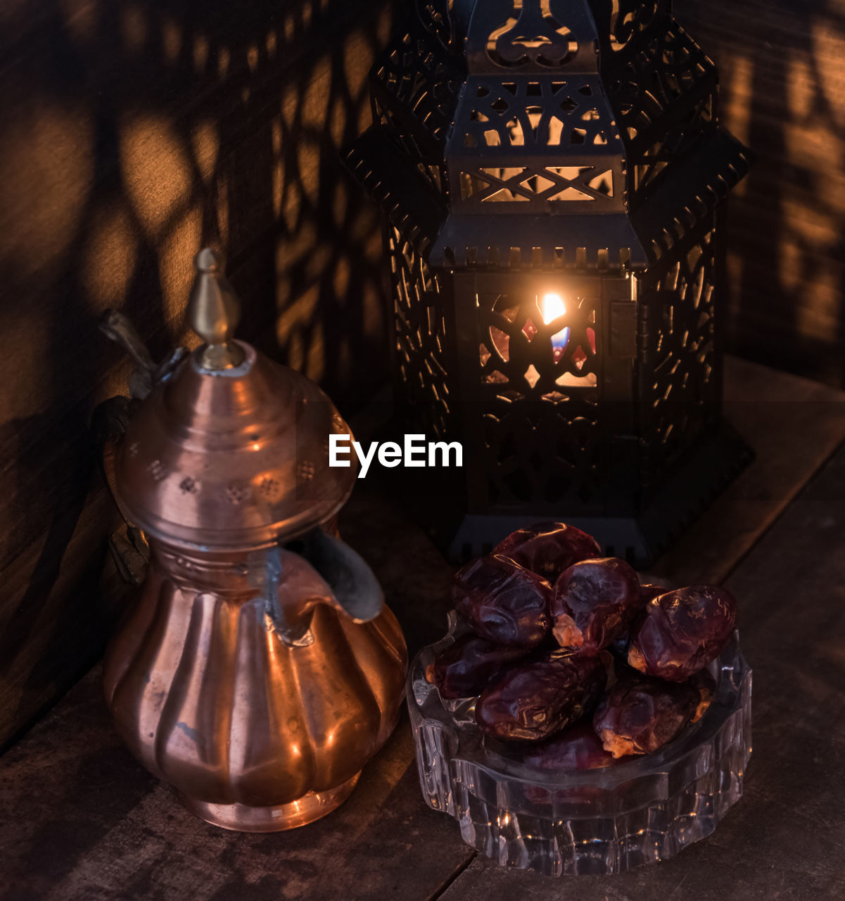 High angle view of antique teapot and lantern with raisins on table