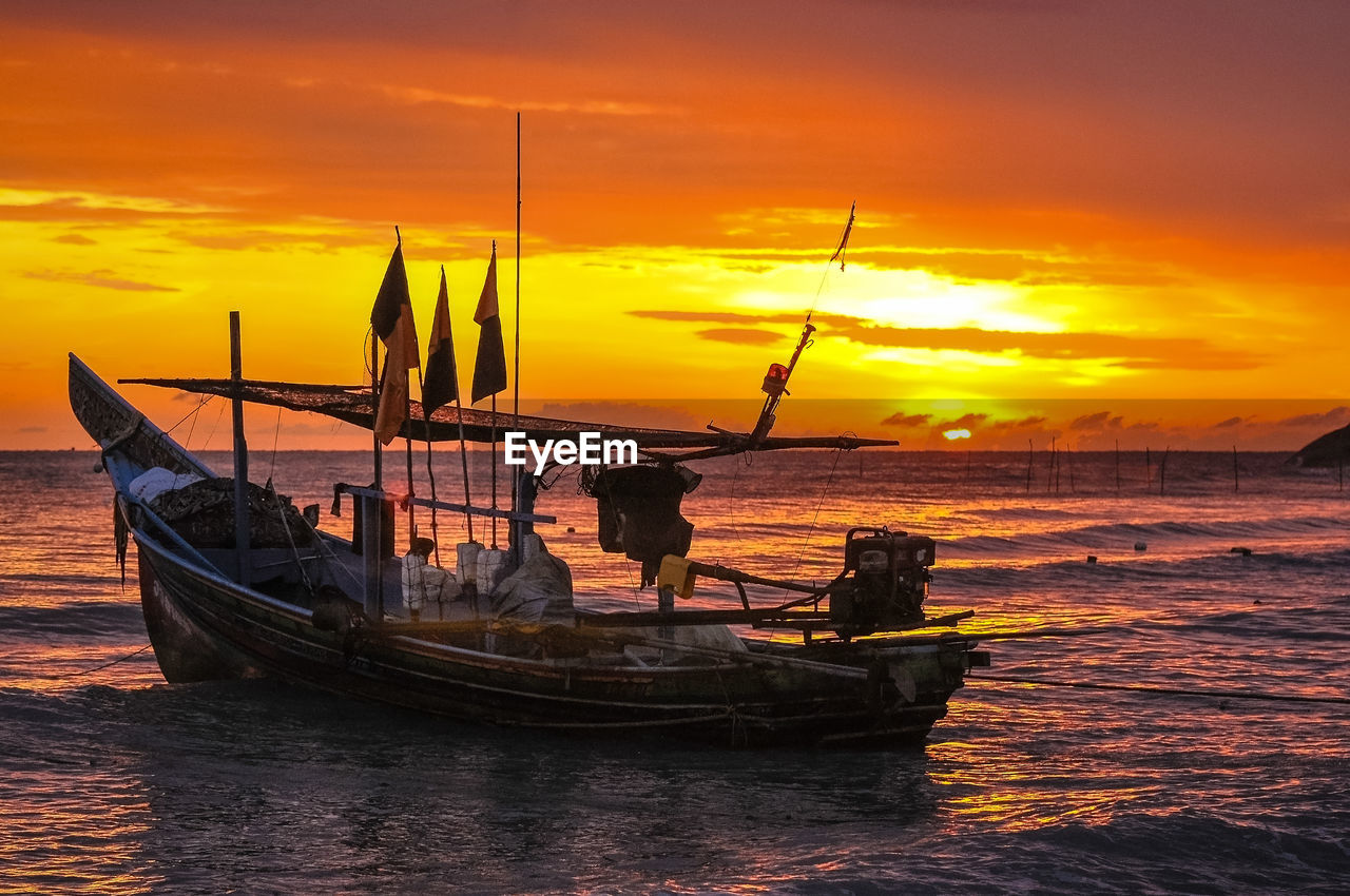 SILHOUETTE FISHING BOAT IN SEA AGAINST SUNSET SKY