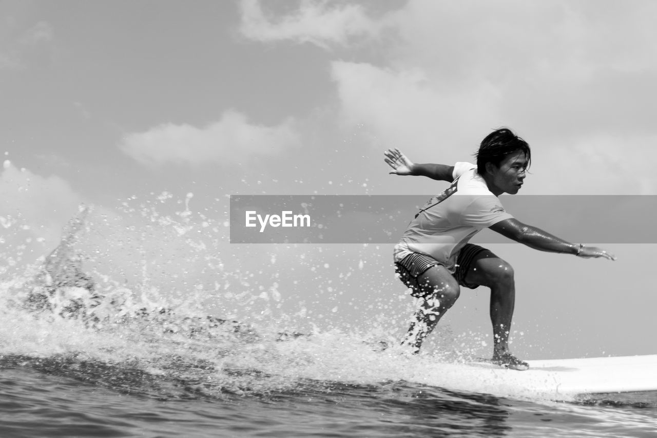 Side view of man surfing in sea against sky