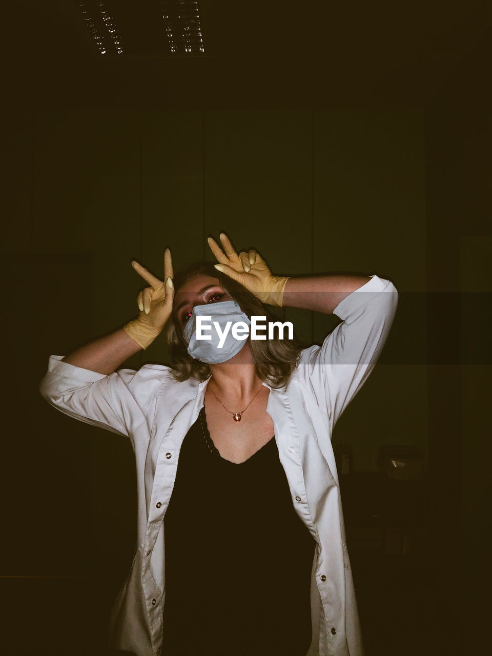 Portrait of woman wearing mask gesturing in darkroom