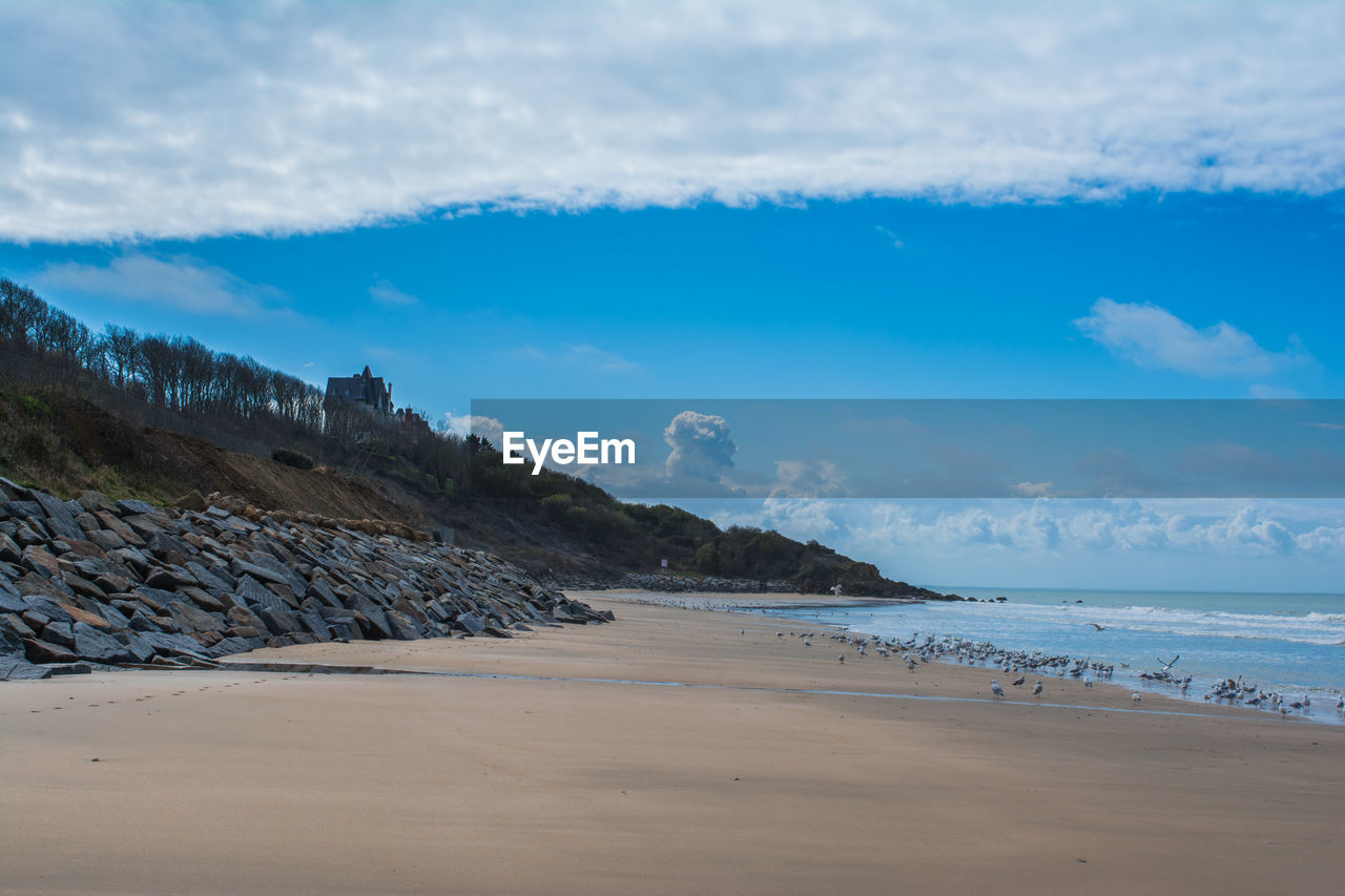 VIEW OF BEACH AGAINST CLOUDY SKY