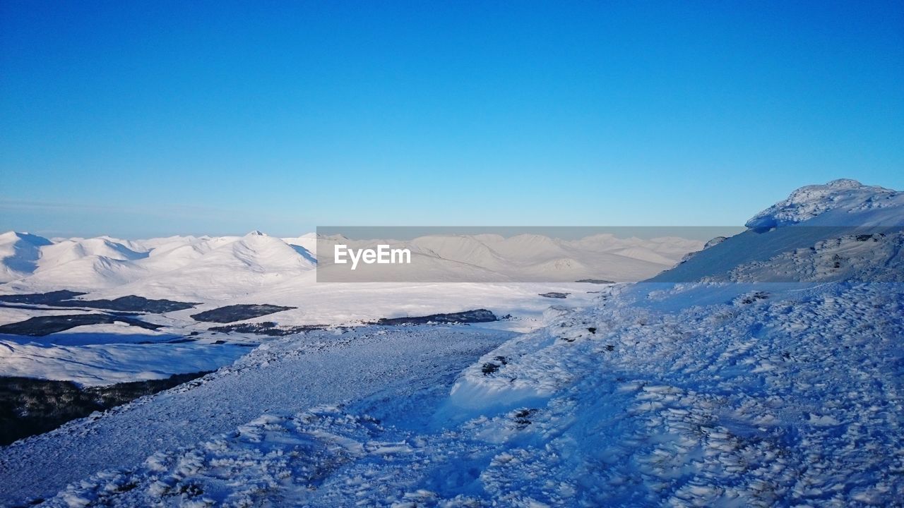 Scenic view of snowcapped mountains against clear blue sky