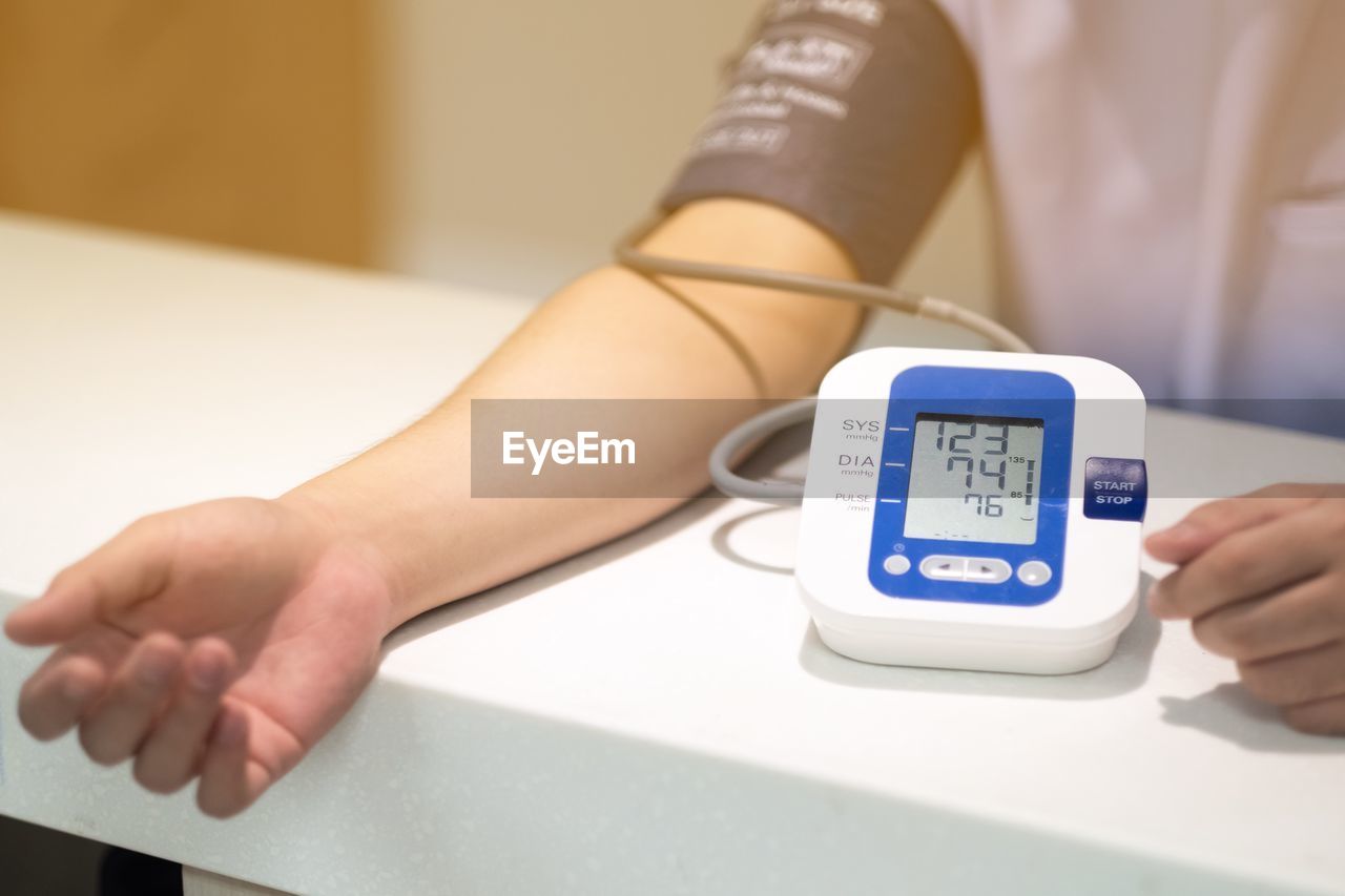 Midsection of man examining blood pressure with gauge on table