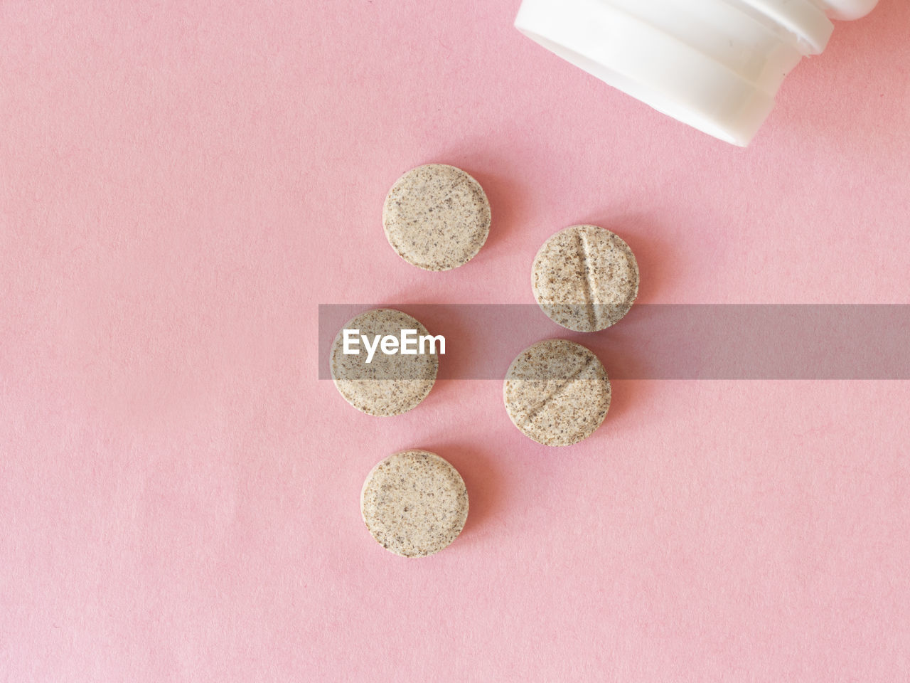 Medicines tablets and white pill bottle on pink background