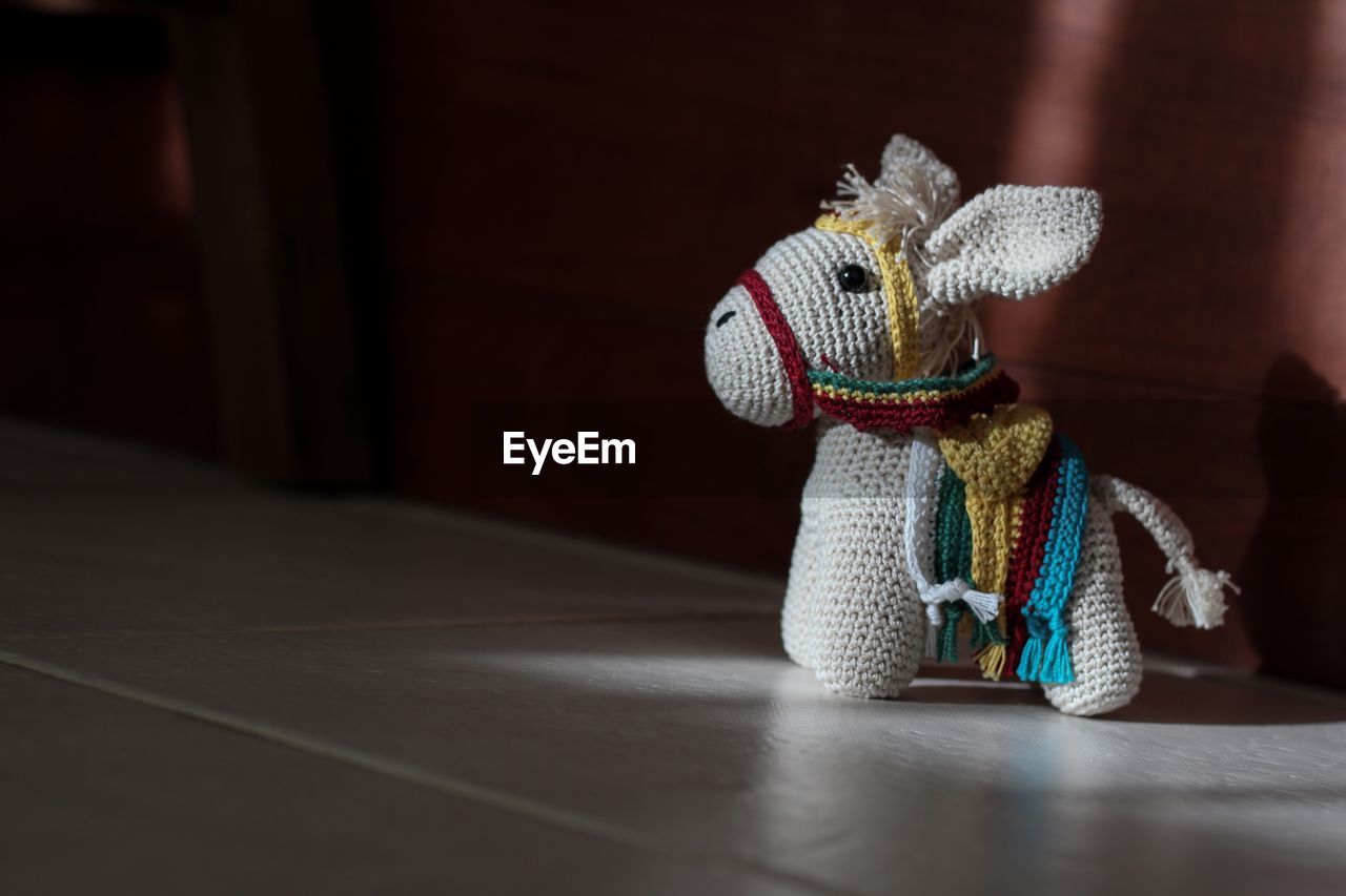 Close-up of knitted donkey toy on tiled floor at home