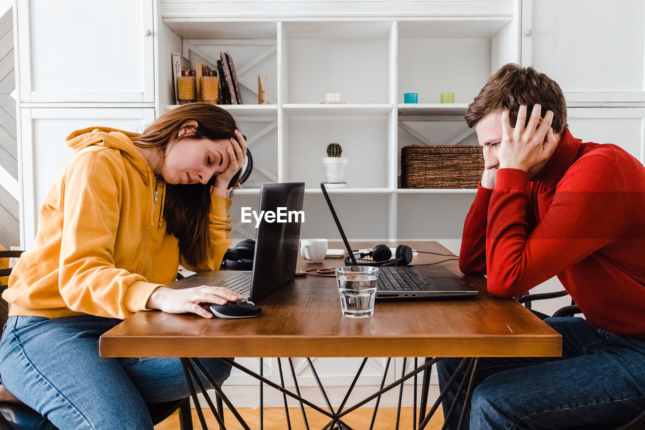 Tired man and woman working at home in the same room. sharing workplace. 