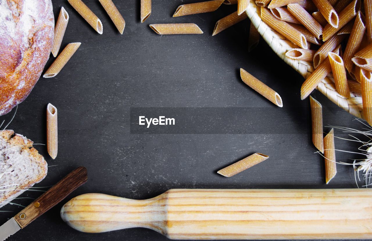 Directly above shot of raw pastas and rolling pin on table