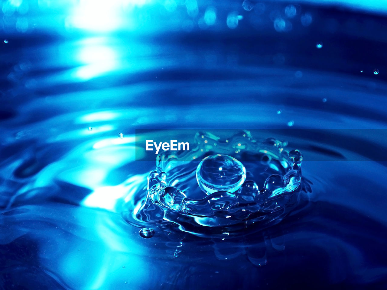 CLOSE-UP OF WATER DROP FALLING ON BLUE SURFACE