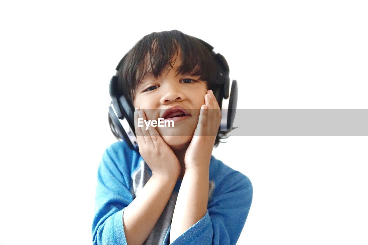 Cute boy listening music against white background