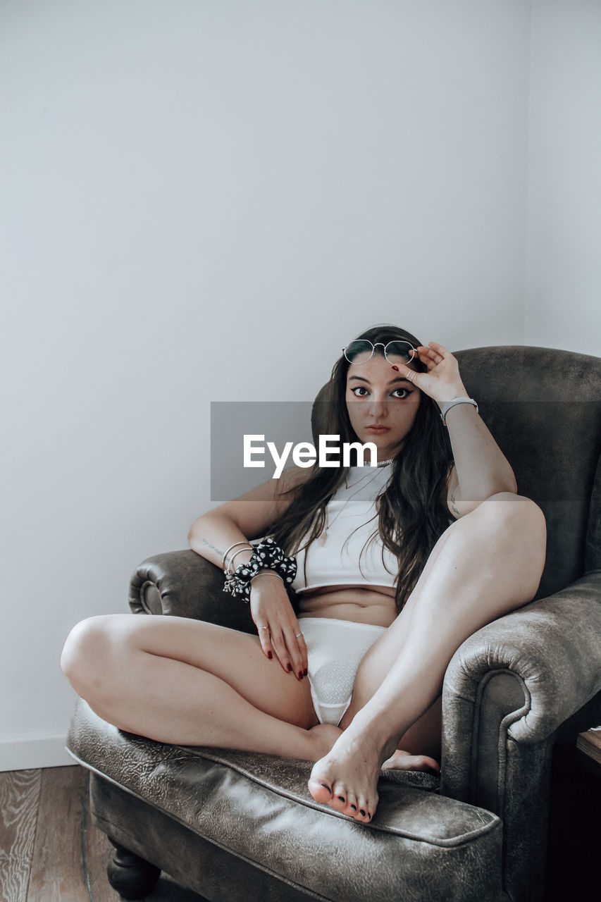 Portrait of young woman sitting on sofa at home