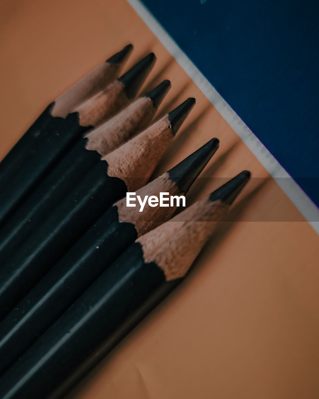 Macro shot of black pencils with a mix of orange and blue background.