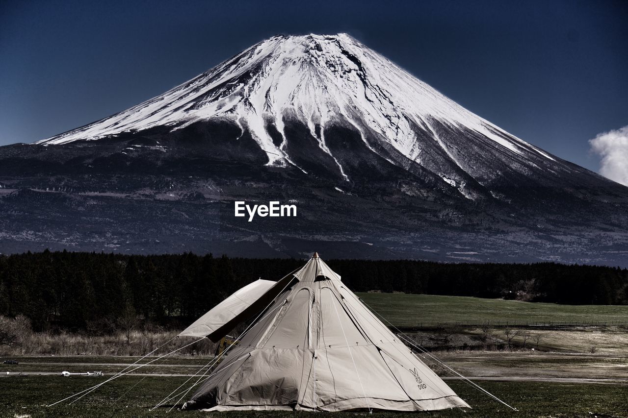Tent on field with snowcapped mountain in background