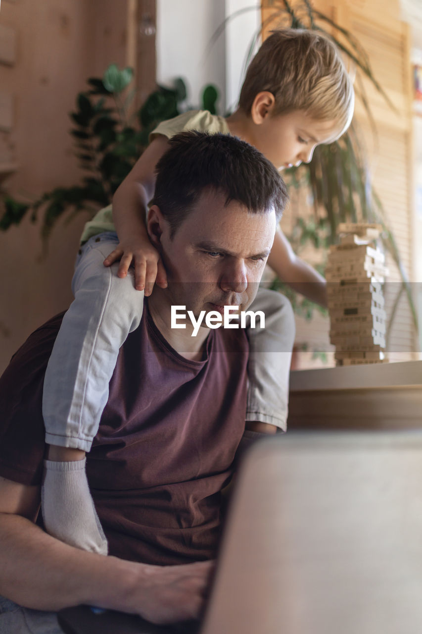 boy looking away while sitting on table at home