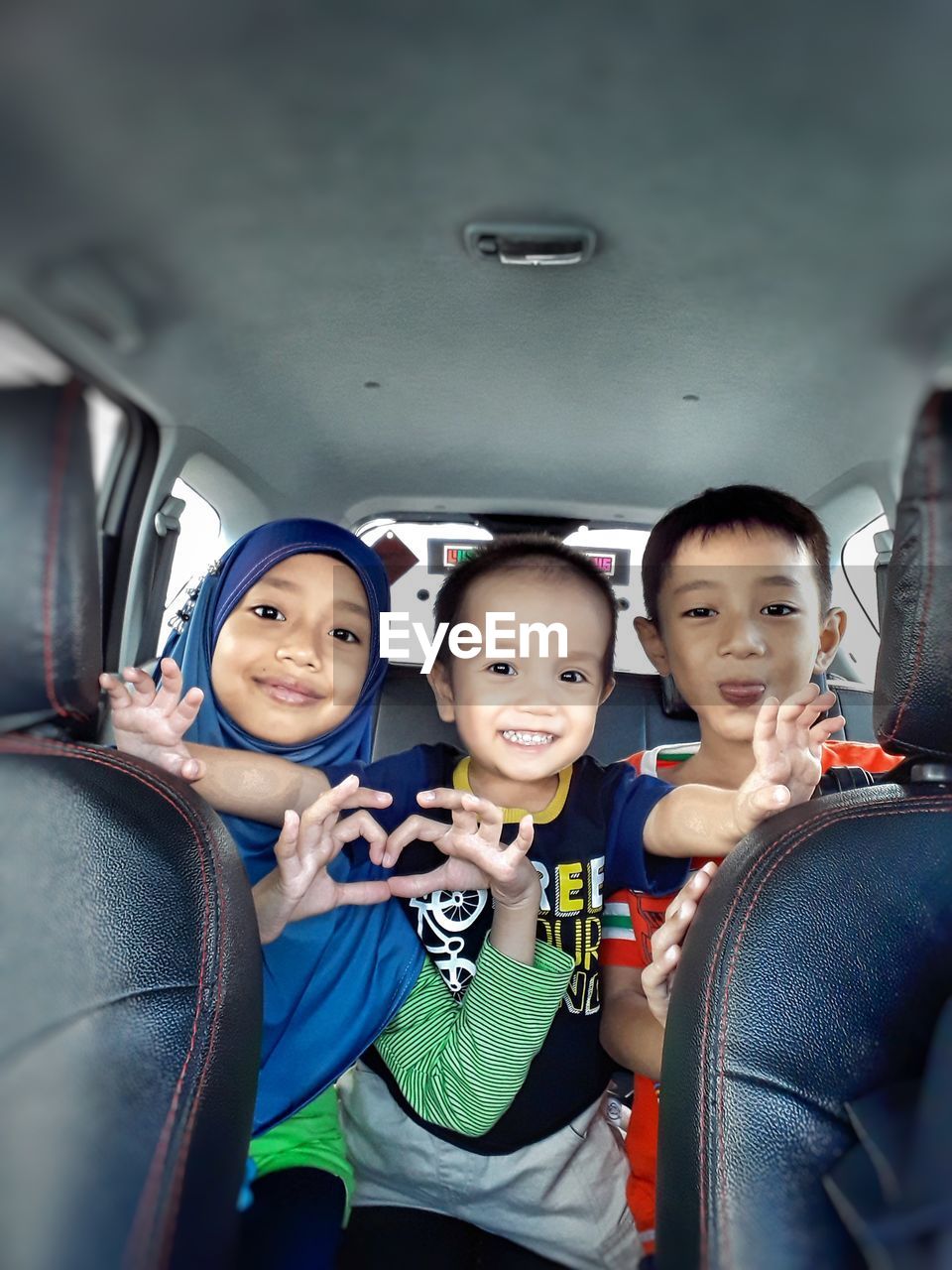 Portrait of smiling siblings sitting in car
