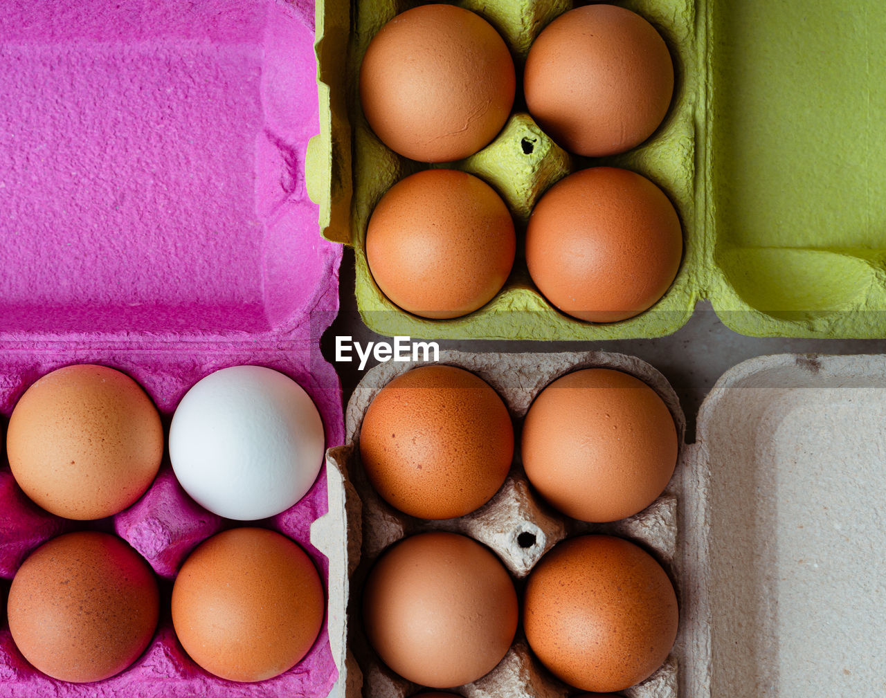Fresh brown and white eggs in colored cardboard containers. closeup view, flat layout. 