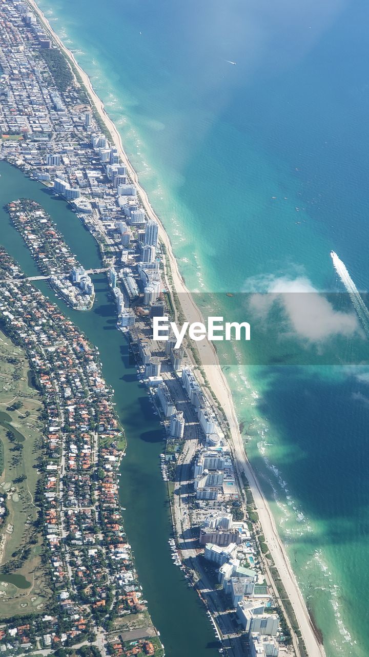 Aerial view of buildings by sea during sunny day