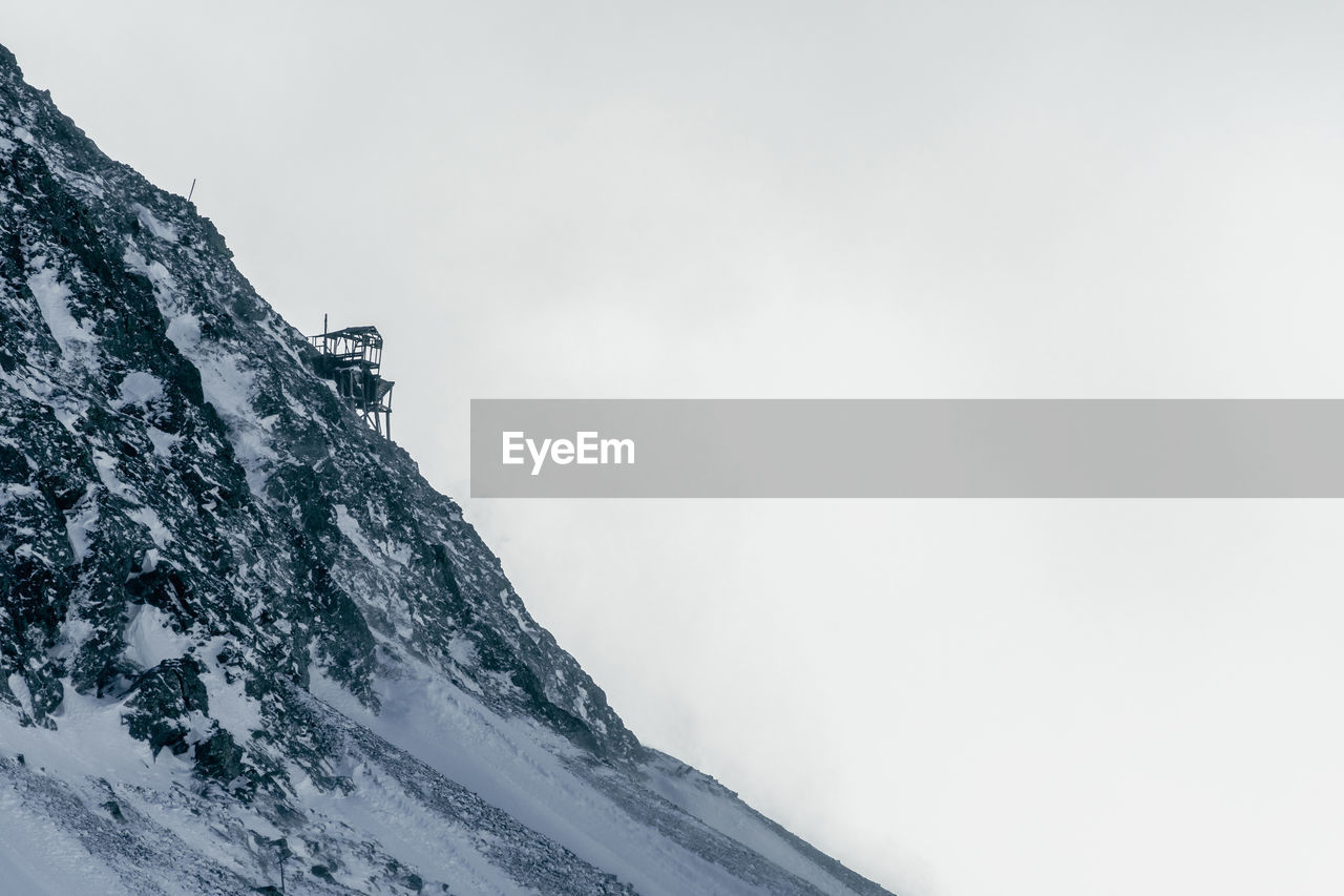 Low angle view of snowcapped mountain against clear sky