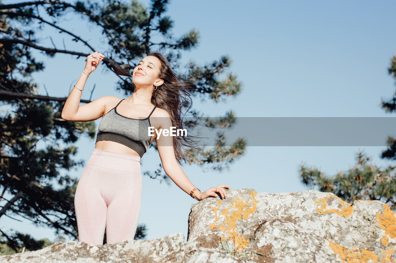 Portrait of young woman standing against sky