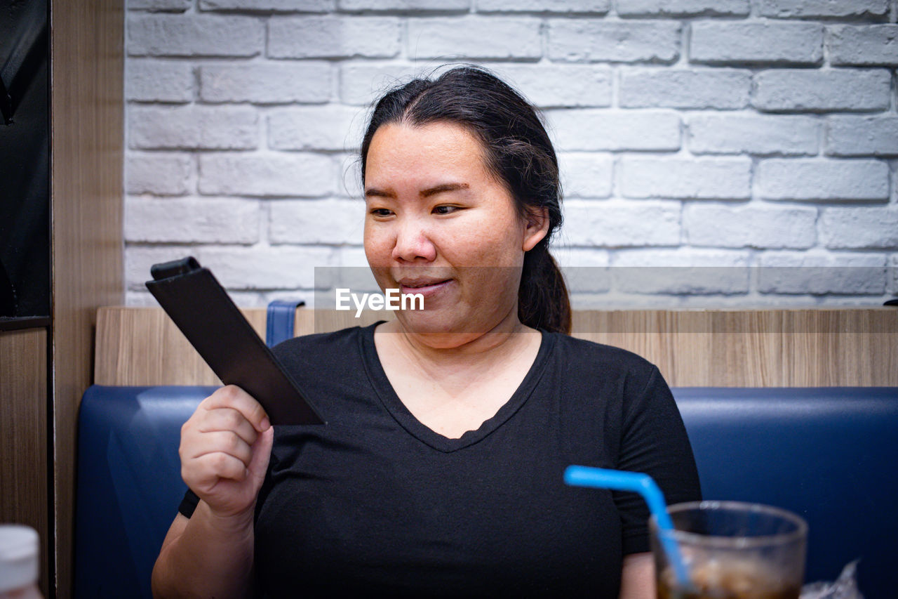 Woman holding bill sitting at restaurant