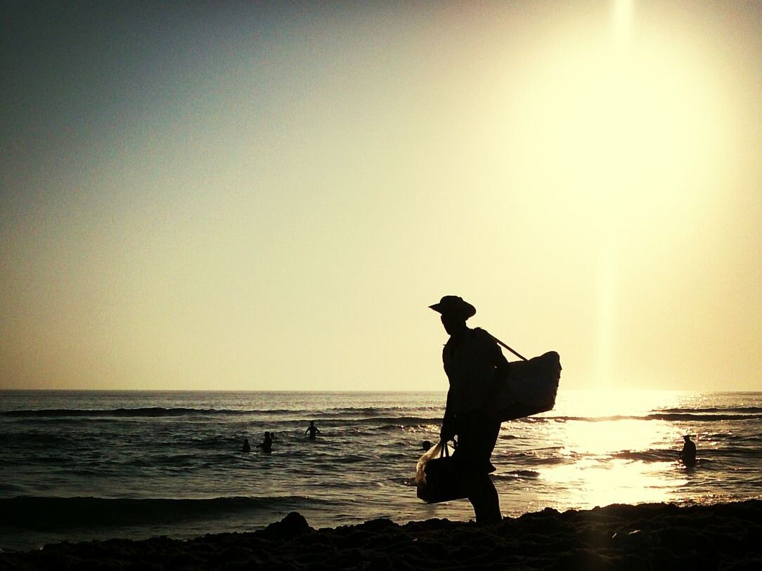 Side view of a silhouette man walking on calm beach