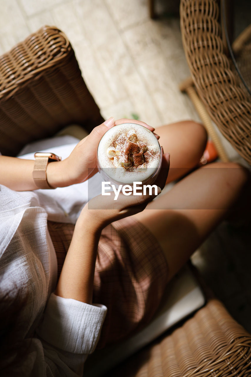 Midsection of woman holding coffee cup on table